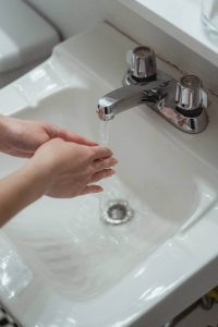 woman washing her hands under a faucet 